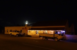 Night view of Perlman House Restaurant and Pub with full moon peaking over the roof and the local pub goers vehicles outside